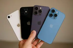 Quatre modèles d’iPhone tenus en main – iPhone SE blanc, iPhone 11 noir, iPhone 13 Pro violet, et iPhone 14 bleu – guide d’achat smartphone Apple occasion en Tunisie