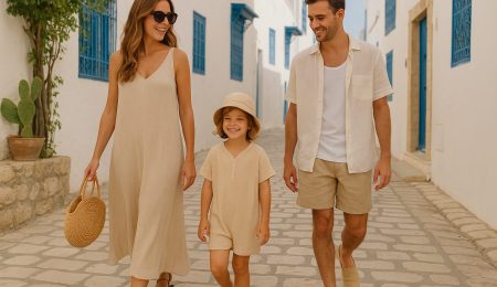 Look estival 2025 en Tunisie : femme en robe fluide, homme en tenue légère et enfant en combinaison dans une ruelle tunisienne