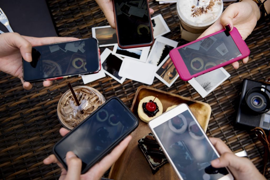 Personnes utilisant des smartphones autour d’une table de café