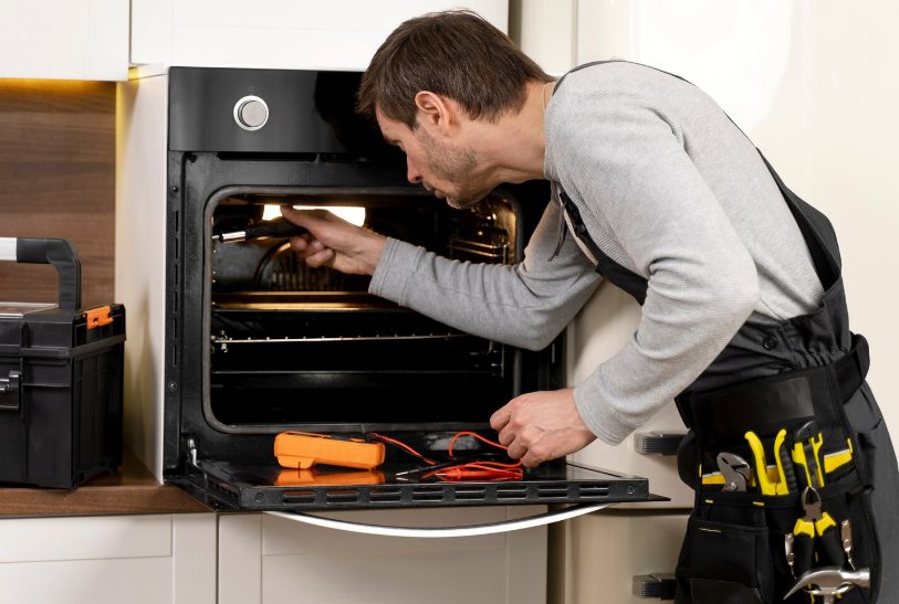 Réparateur professionnel intervenant sur un four avec outils spécialisés