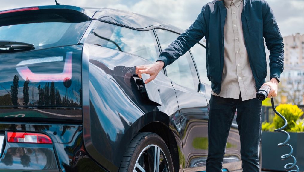 Homme branchant le câble de recharge d'une voiture électrique noire
