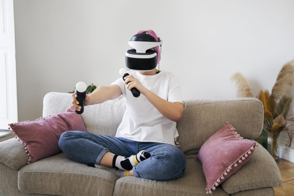 Joueuse avec casque de réalité virtuelle PlayStation, assise sur un canapé à la maison
