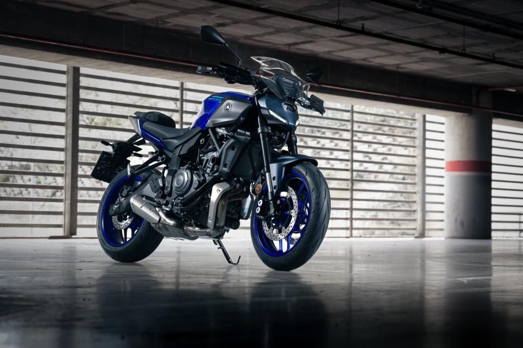 Moto roadster bicylindre bleu parking souterrain vue trois-quarts