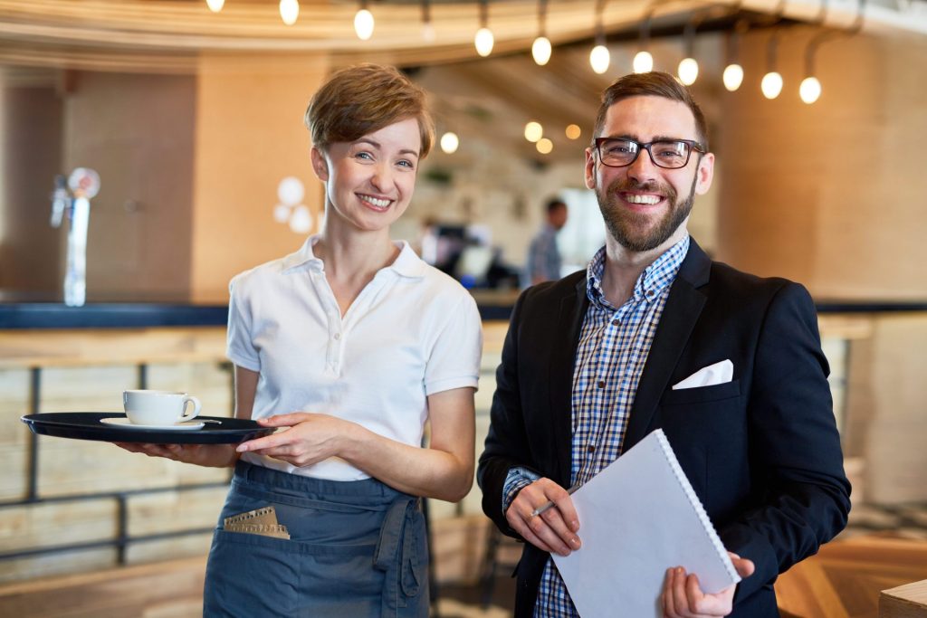 serveuse et responsable souriants dans un hôtel ou espace de restauration