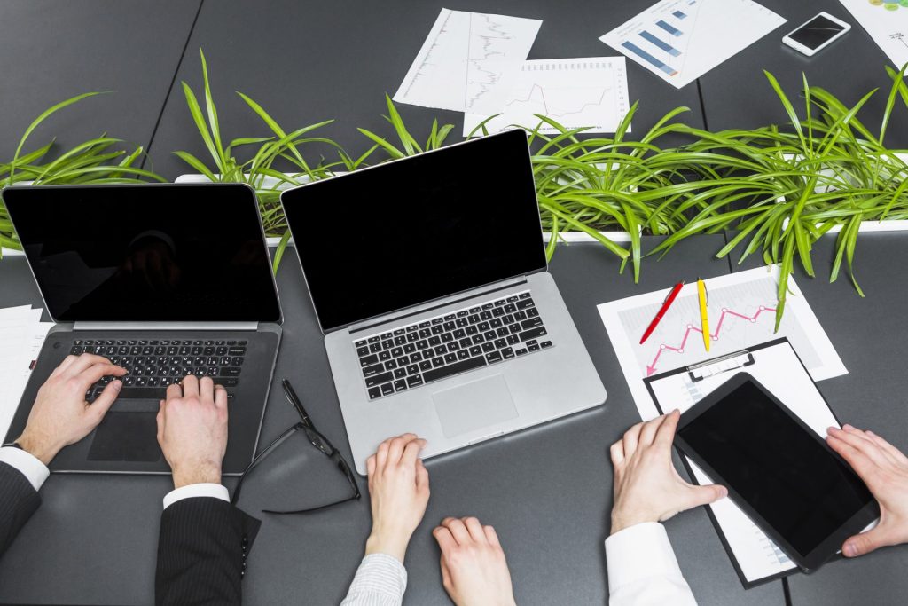 Deux ordinateurs portables côte à côte sur un bureau avec graphiques et documents financiers