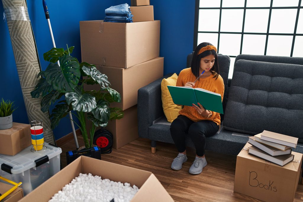 Jeune fille assise sur un canapé avec des cartons de déménagement