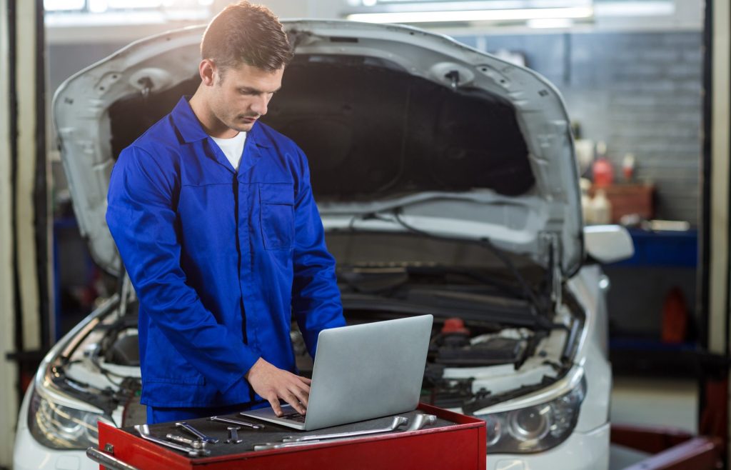 Mécanicien réalisant un diagnostic moteur sur ordinateur avant l'achat d'un utilitaire d'occasion
