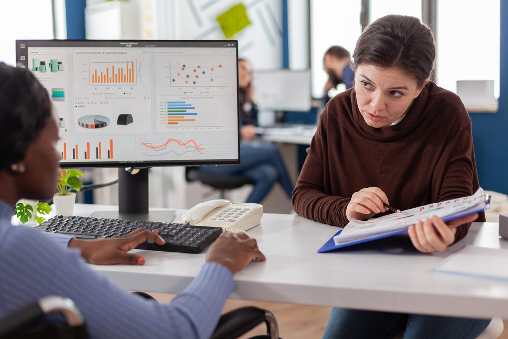 Professionnel avec son collége analysant des données sur ordinateur dans un environnement de travail