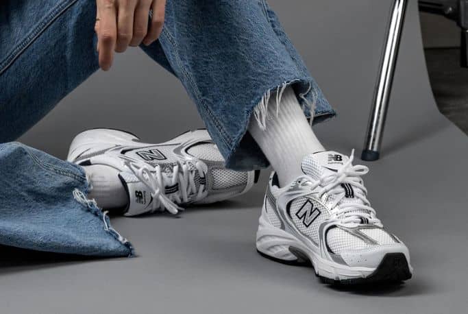 New Balance blanches et grises portées avec un jean et des chaussettes blanches