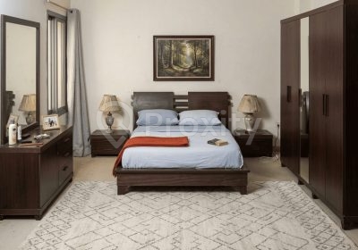 Chambre à coucher adulte en bois foncé avec lit deux places, tables de nuit, coiffeuse avec miroir et dressing
