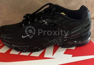 Nike Air Max Plus 3 noires pointure 42 posées sur une boîte Nike rouge
