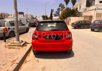 Vue arrière d’une Skoda Fabia rouge 2015 stationnée dans une rue à Tunis
