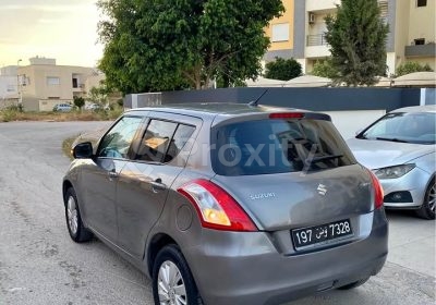 Suzuki Swift grise 2017 vue arrière gauche stationnée dans un quartier résidentiel à Tunis