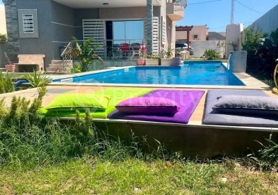Grande piscine devant la villa de vacances à Beni Khira avec transats colorés