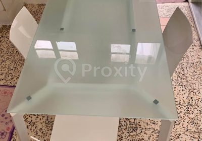 Table à manger en verre avec quatre chaises blanches à Ras Jebel