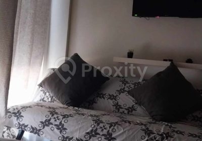 Vue intérieure du studio S+0 avec espace de couchage et télévision murale